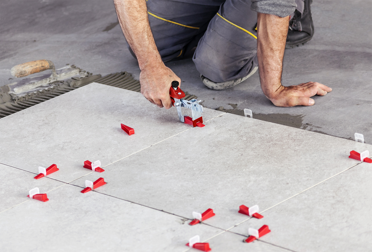 Ceramic Tiles. Tiler placing ceramic wall tile in position over adhesive with lash tile leveling system