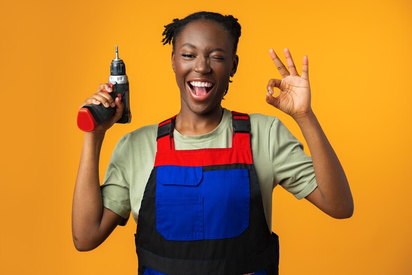 black african american female model uniform holding screwdriver repair tool against yellow back 93675 137674